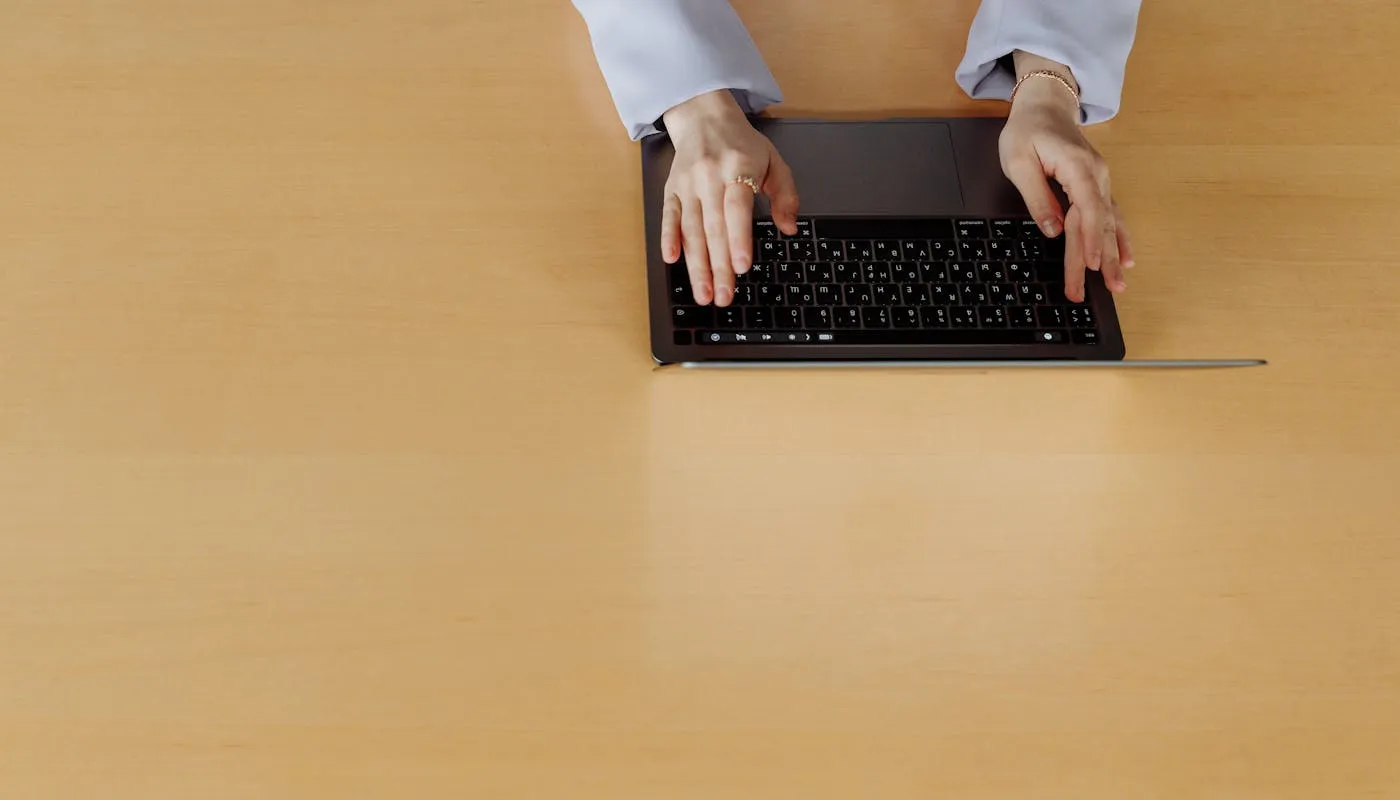 Top view of hands typing on laptop at a minimalist desk